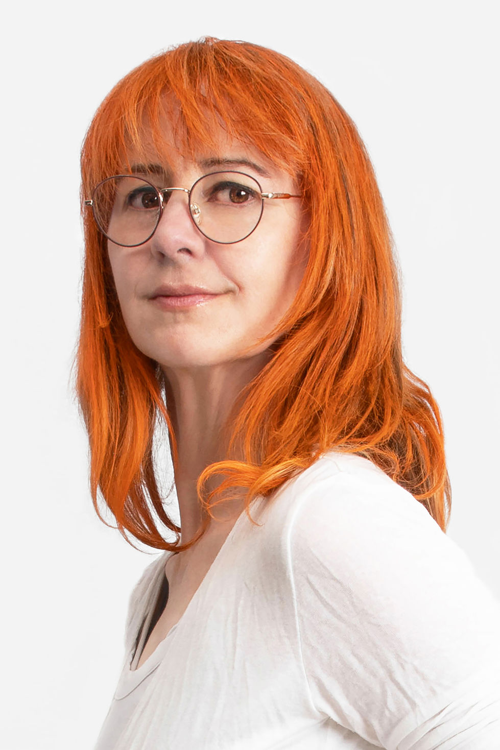 Portrait d'une femme rousse sur fond blanc avec des lunettes qui regarde l'objectif