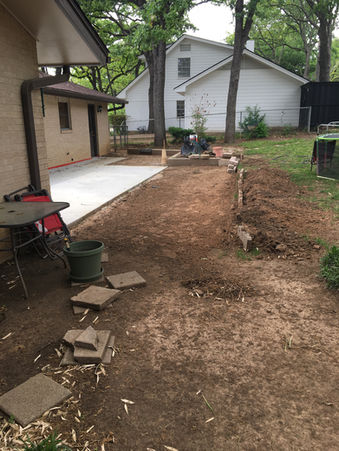 Concrete patio construction, backyard view. House and trees in background.