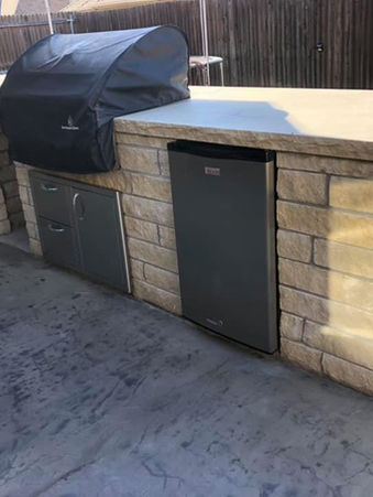 Outdoor kitchen with grill, refrigerator, and countertop; brick surround. Kirkland Masonry and Concrete