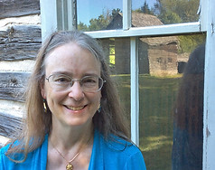 Kathleen Ernst standing in front of a cabin window