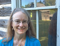 Kathleen Ernst standing Infront of a cabin window
