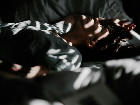 A man trying to sleep with light streaming in from a window
