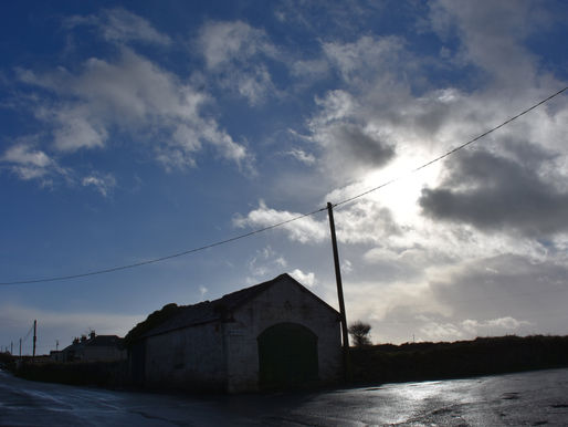 Panoramic view of Old Head peninsula in Kinsale, County Cork Ireland — the ivy-leaf shaped headland where Donna Troy Cleary's maternal ancestors lived before emigrating in the early 1800s, with the 1677 fortress ruins visible on the winding coastal road, photographed during her 2017 ancestral pilgrimage. ower silhouette: "The crumbling medieval tower at Old Head Kinsale silhouetted against the Atlantic Ocean at dusk — photographed by Donna Troy Cleary during her 2017 ancestral pilgrimage to her mother's family homeland in County Cork Ireland. Full fort under storm clouds: "The 1677 Old Head fortress standing under dramatic storm clouds on the Kinsale peninsula, County Cork Ireland — photographed by Donna Troy Cleary during her 2017 ancestral pilgrimage.Churning ocean from cliff edge: "The churning Atlantic Ocean and jagged rocks seen from the unguarded cliff edge at Old Head Kinsale — photographed by Donna Troy Cleary during her 2017 ancestral pilgrimage to County Cork Ireland Cliffl