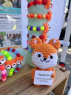 Close-up of the You Are a Gardener® booth table with colorful Foxie beaded bracelets, plush fox, and vibrant display materials celebrating Bottle Hill Day.