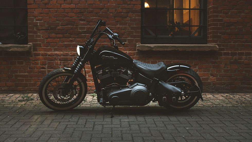 black cruiser motorcycle parked beside a brick wall