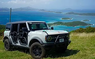 Scenic overlook of St. John's green hills and turquoise Caribbean coastline during a private full-day island sightseeing tour.