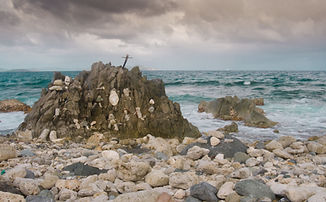 Hikers walk toward Drunk Bay with rocky shoreline and blue Caribbean water in the background.