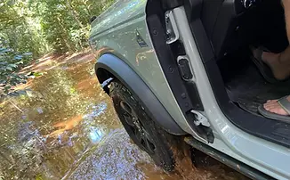 Open air Ford Bronco splashing in a mud puddle, offroading on St. John, USVI