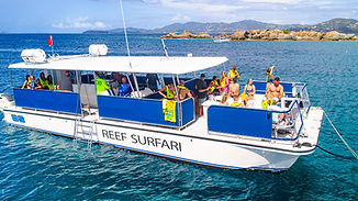 Power catamaran Reef Surfari navigating turquoise water near coral reef in Virgin Islands National Park.