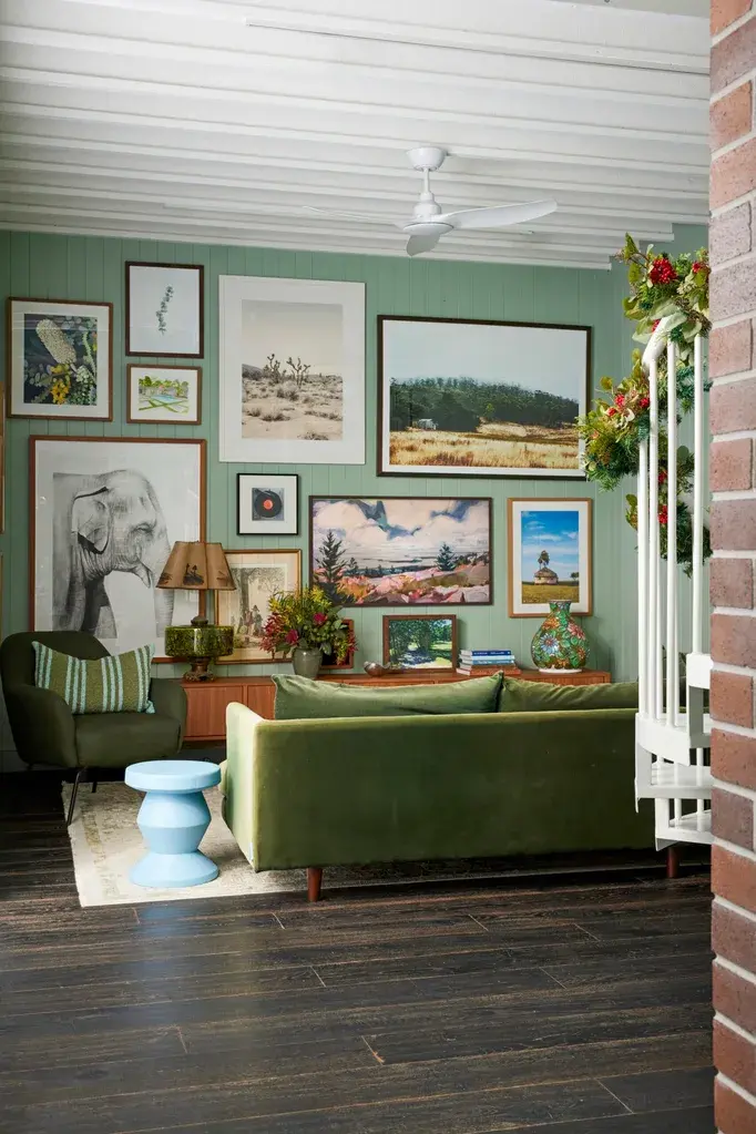 Eclectic styled lounge room saturated with the color green displaying art and a collection of furniture items