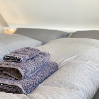 Stapel Handtücher auf Bett in Ferienwohnung Wenningstedt