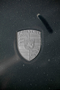 Before - A Porsche emblem on a Porsche 911 Carrera S caked in dust. This image shows the emblem before cleaning.