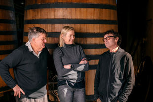Winemakers talking by large wine barrels in New Zealand.