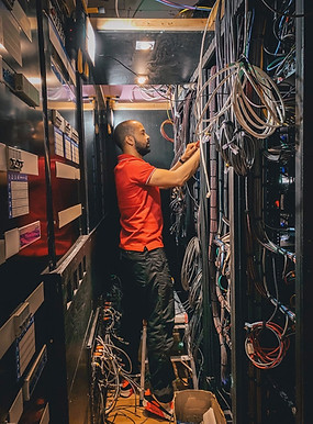 Paul Mcken of Electric Frog home automation specialist working in a server room full of racks and cables