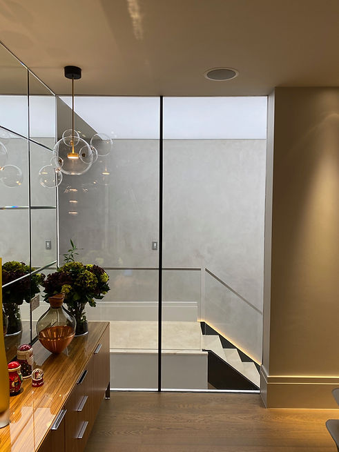 luxury home hallway with staircase lit up by lutron lighting