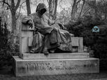 Statue auf einem Sockel, nachdenklich sitzend, mit einem Schreibinstrument in der Hand, Anonymus-Statue, Schwarz-Weiß-Fotografie