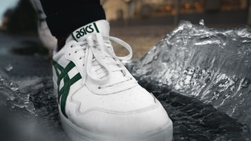 Asics Schuh, der in eine Wasserpfütze tritt