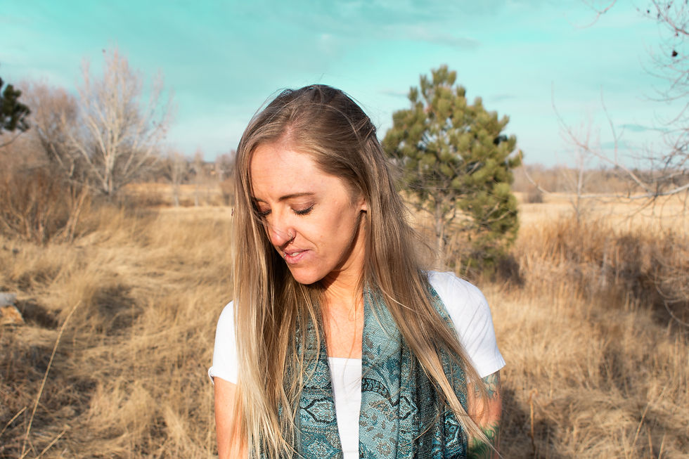 Blonf girl in a field wearing a scarf with a tree in the background