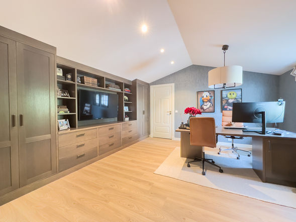 Utforsk dette elegante hjemmekontoret med et to-veis skrivebord designet av kunden selv. Bokhyllen i beiset eikefinér har innebygget TV og lukkede skap til printer og kontorrekvisita. Farge: Antikk gråbrun, med håndtak i brunt skinn og messing.