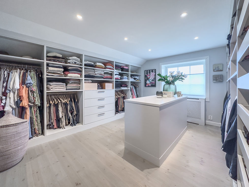 Oversiktsbilde av et måltilpasset walk-in closet med øy, åpne hyller, heng og radiatorskjuler.