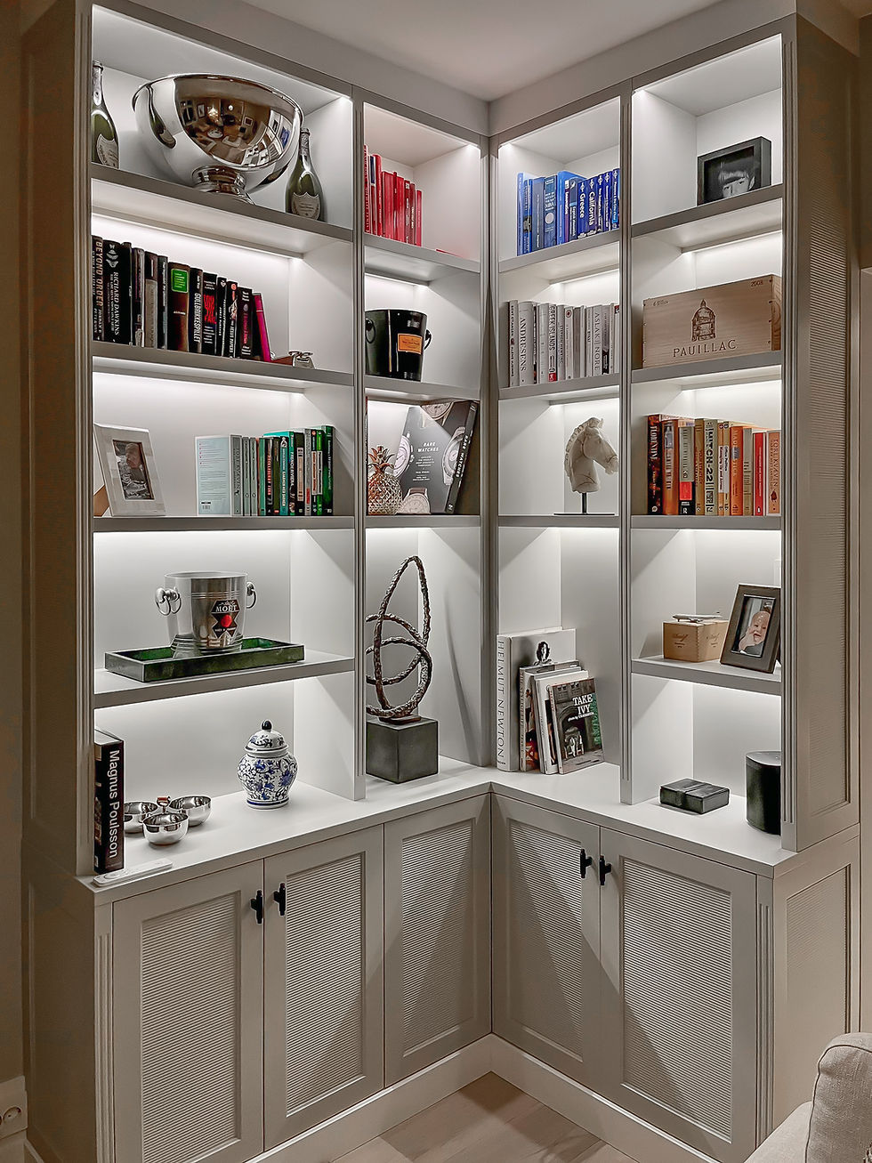 Elegante fronter med rille-mønster og vanger med spor, Belyste reoler på mål som er tilpasset innholdet i bokhyllen etter kundens ønske. Jotun Smooth White farge og Arpa T knotter i sort fra Beslag design