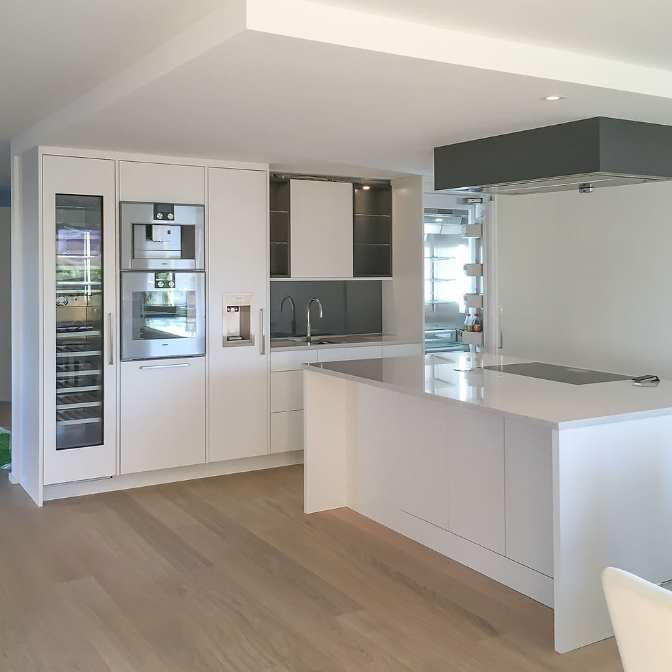 Dette funksjonelle kjøkkenet kombinerer eleganse og praktiske løsninger for hjemmekokken. Slette overflater i Jotun klassisk hvit og detaljer i Peppergrå gir et sofistikert preg sammen med hvitevarene fra Gaggenau. En stor øy med takventilator gir et luftig inntrykk og fullfører det stilrene designet.