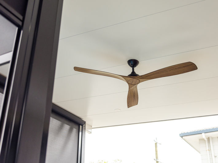 Exterior patio with a modern timber-look ceiling fan installation.
