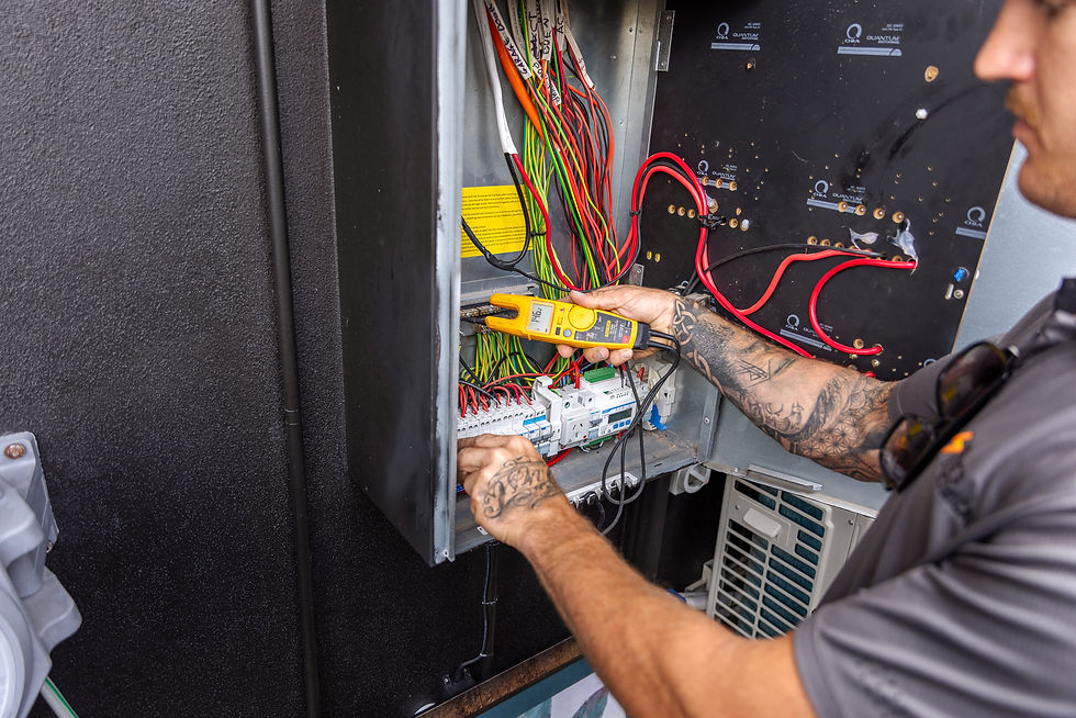 Expert electrician performing safety testing and checks on a main electrical switchboard panel.