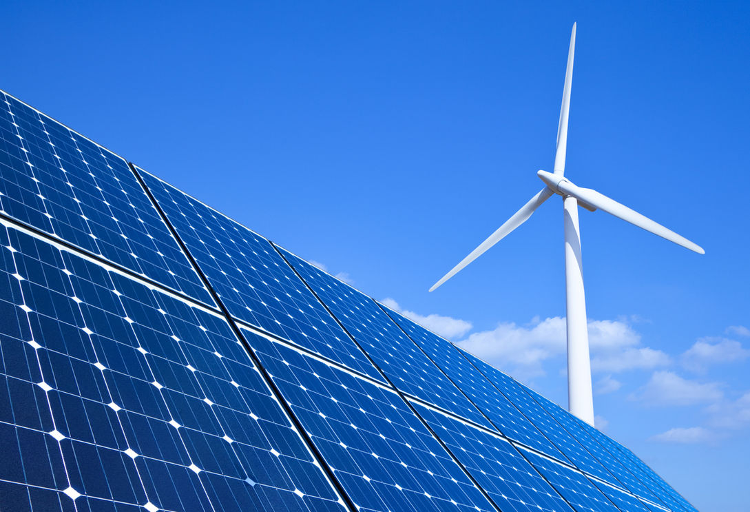 Solar panels and wind turbine against bl
