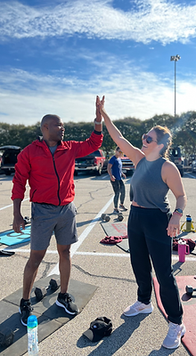 Two people high fiving each other, workout gear, outside, Camp Gladiator.