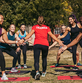 Group fitness class huddling together with a trainer in red Camp Gladiator.