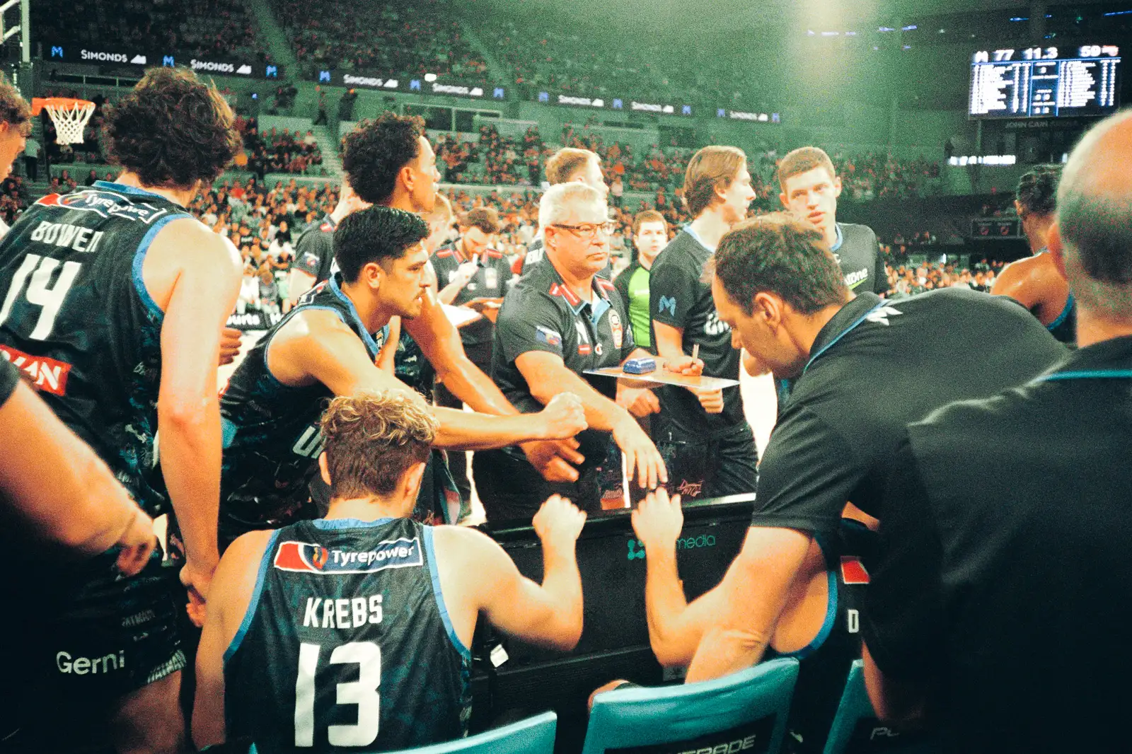 melbourne united team in a time out putting their hands in together