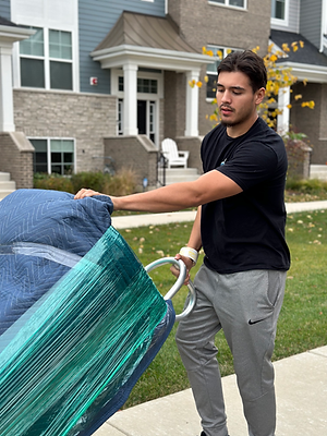 Dos Manos Moving employee moving a love seat with a doll.