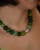 A necklace of strung handblown hollow glass beads in rich greens, with a hollow sterling silver bead and handmade sterling silver clasp.