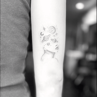 a black fine lined tattoo of a person that has plants in place of a of the nose up
