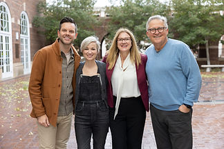 Jaime Clark-Soles is standing outdoors, smiling, alongside Rev. Dr. George Mason and two young adults, one man and one woman, on a cool, gray day.