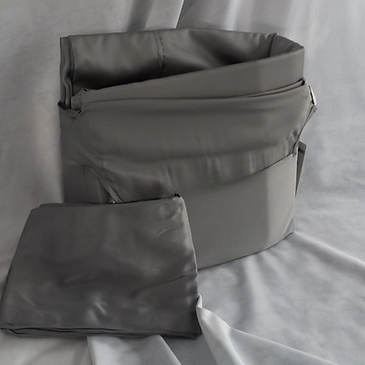 Dark grey bamboo sheets, on a grey background. The pillowcase is laying beside the sheet container.