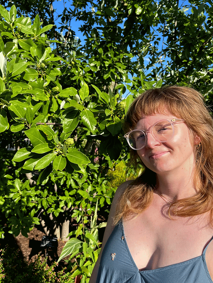 GIF of Caitlin Whyte posing in front of a bush on a sunny day