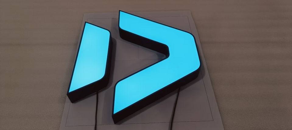 Illuminated acrylic logo sign in cyan — custom 3D brand signage
