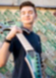 senior boy holding guitar standing in front of a license plate wall