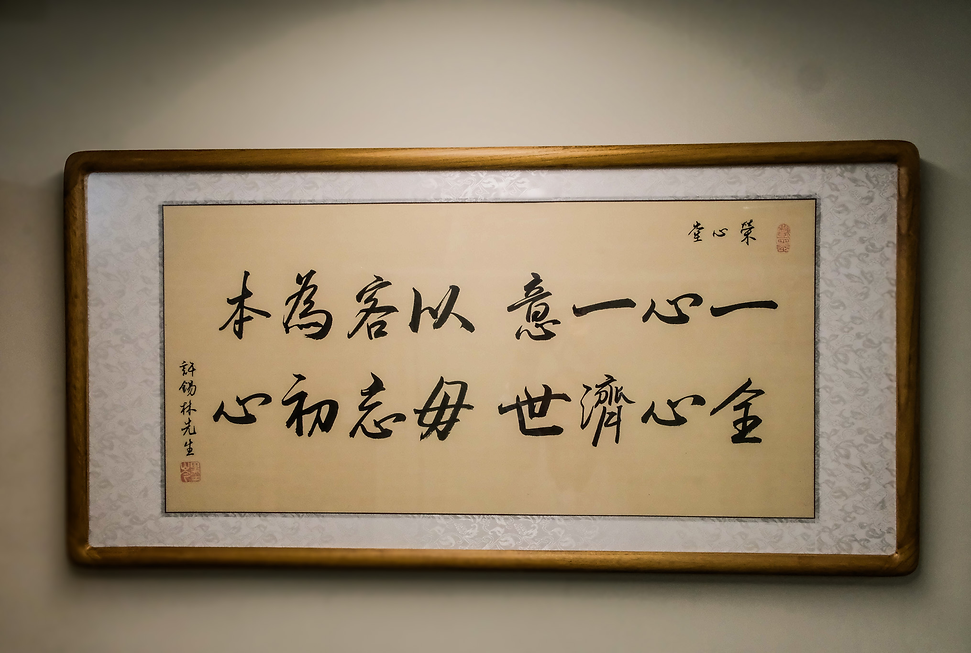 懸掛在榮心堂診所由毛筆寫的宗旨「一心一意、以客為本、全心濟世、毋忘初心」