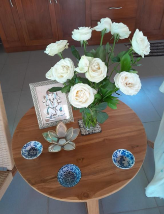 Round solid wood coffee table styled with white roses and decorative accessories.