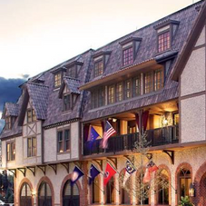 Grand Bohemian Asheville hotel exterior featuring Tudor-style architecture, arched entrances, and illuminated flags at dusk.