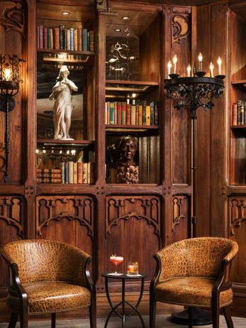Custom teak wood library cabinetry and carved shelving in an intimate lounge or reading room setting.