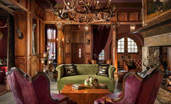 Luxury lounge featuring carved wood wall panels, custom seating, and an antler chandelier.