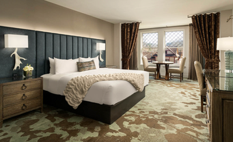 Hotel guest bed with a custom frame, tall upholstered headboard, and bedside table.