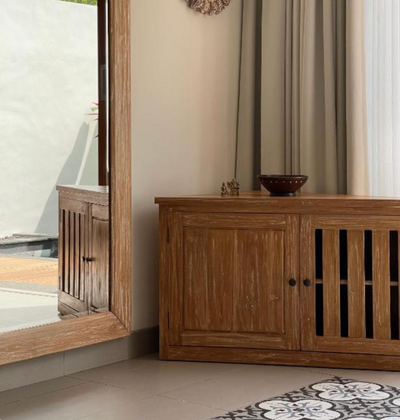 Custom slatted wood storage cabinet beside a window in a villa bedroom.