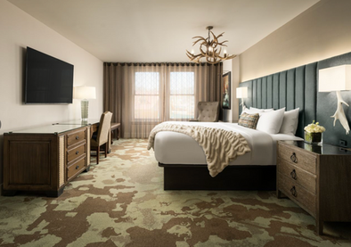 Luxury hotel guest room with a custom bed frame, upholstered headboard, dresser, and desk.
