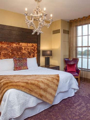 Custom reclaimed-wood headboard and handcrafted teak furniture in a boutique hotel bedroom suite.