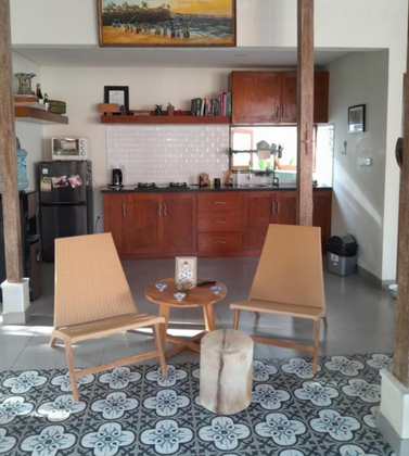 Custom wood kitchen cabinetry with lounge chairs in an open-plan villa interior.
